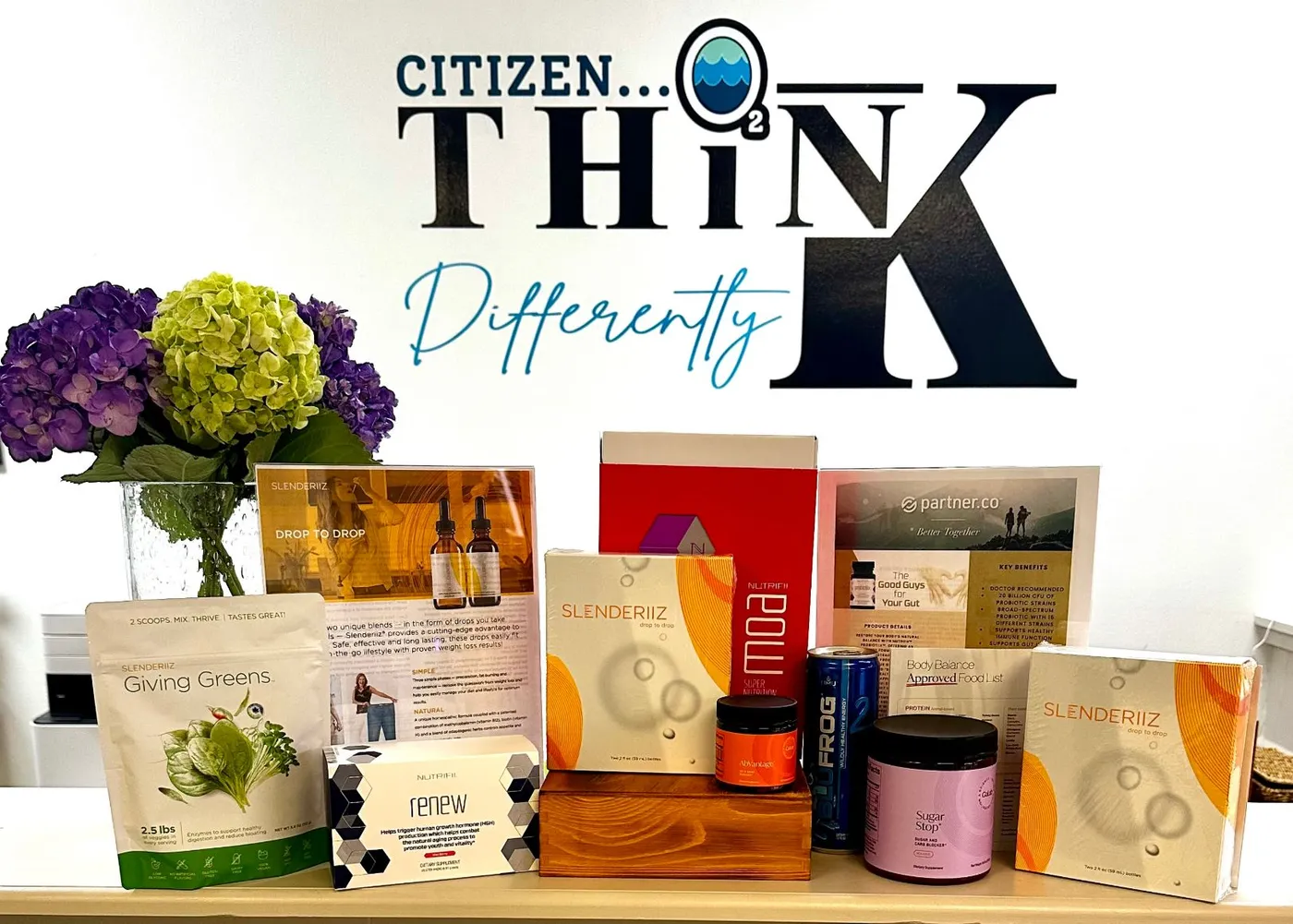 The “Citizen… Think Differently” sign above a display of wellness products at Citizen OxyWellness